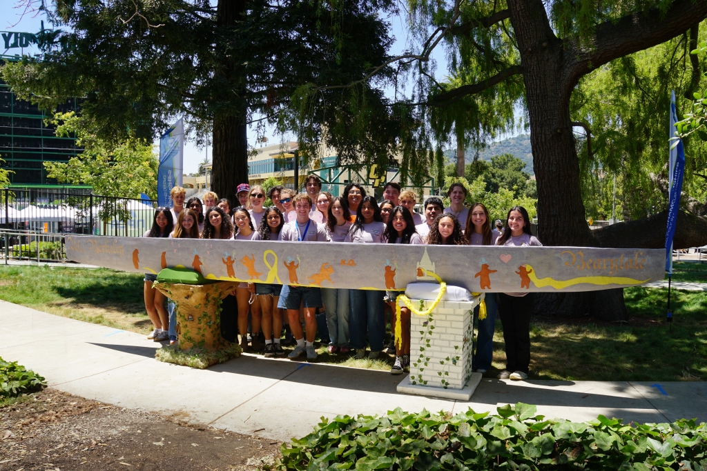 A group photo of the Cal Concrete Canoe team at ASCE Nationals standing in front of their concrete canoe (Photo Credit: Emma Le Coz)