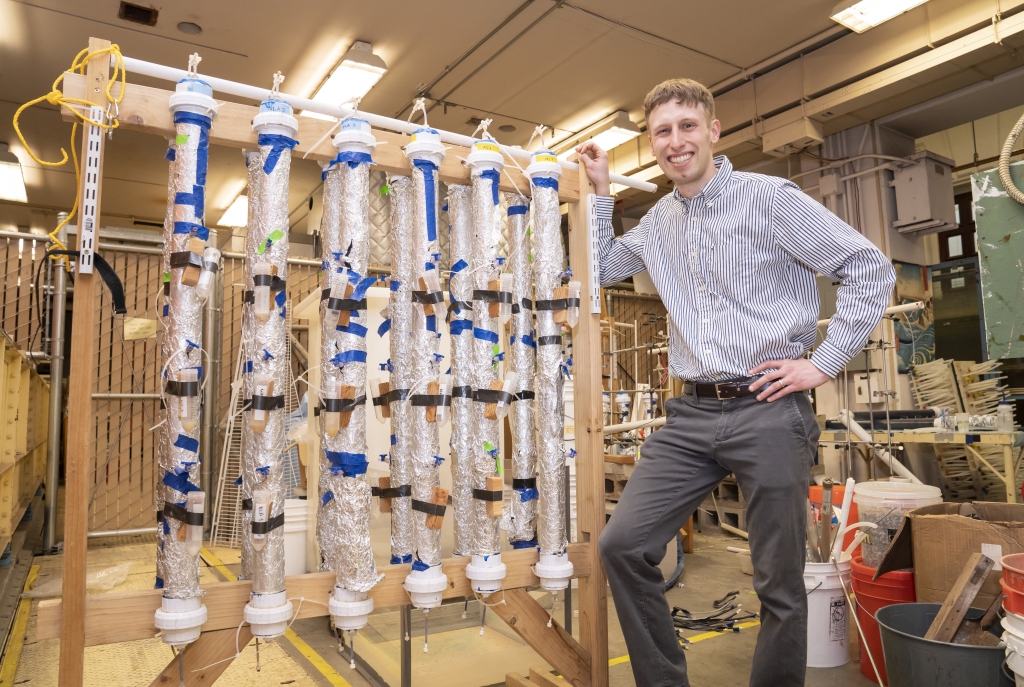 Man standing next to stand holding tubes of sand samples.