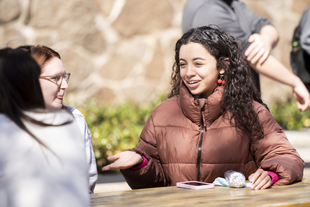 Two students seated outside having a conversation.