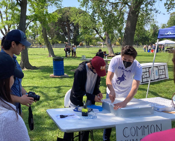 Two students working together at an Earth Day event to demonstrate how to built a homemade air purifier.