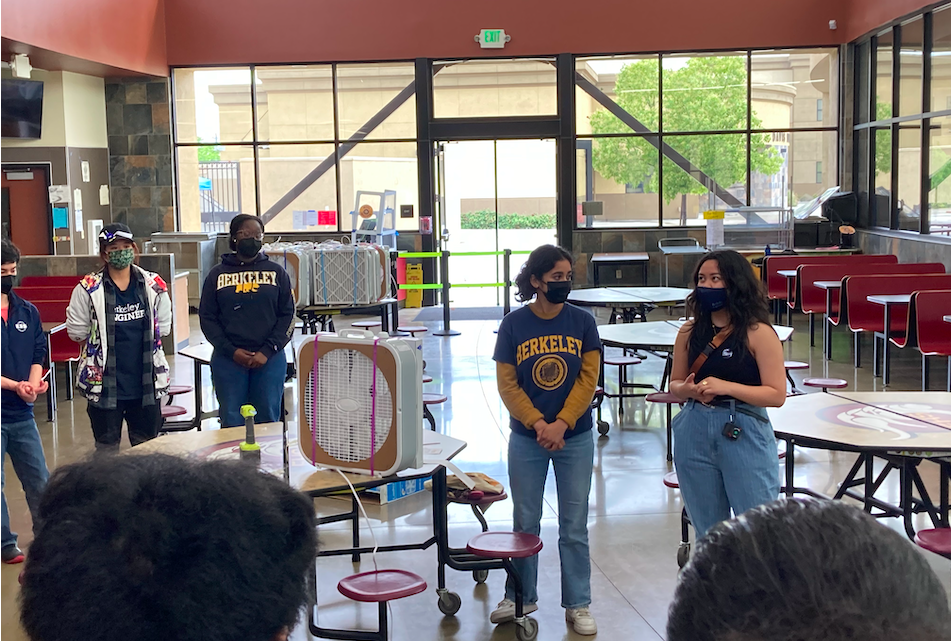 Group of students in assembly hall learning about air pollution and how to build homemade air purifiers.