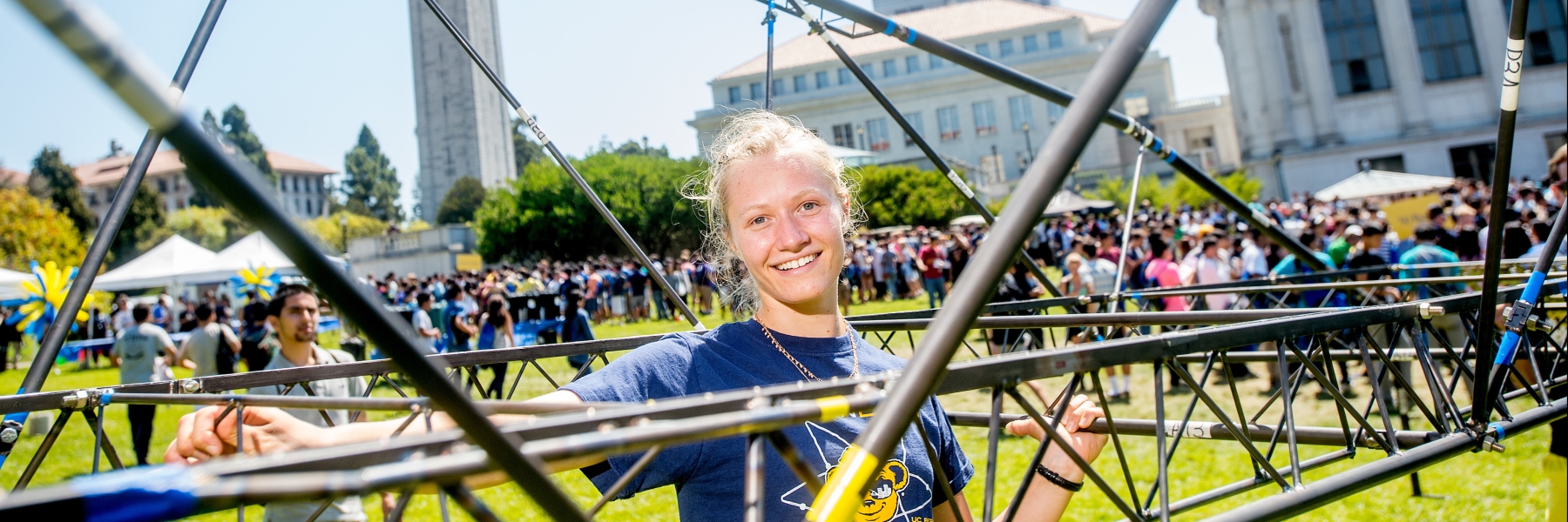 Student posing with steel bridge model on Memorial Glade