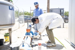 Jay Majmudar, a research and development engineer in Ashok Gadgil's lab at UC Berkeley, collects a water sample while the Rev. Dennis Hutson observes. Gadgil's lab is collaborating with Hutson and other Allensworth community leaders to field test a new arsenic treatment system that could help provide safe drinking water to California's rural communities. (Photo/Caption Credit: Adam Lau & Phys.org)