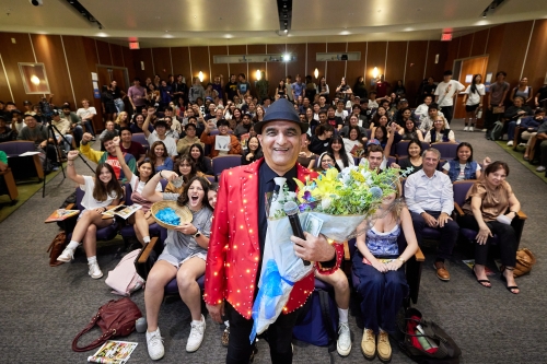 A group picture of attendees of the Engineering is About People event with CSI CEO Ashraf Habibullah wearing a red suit, black top-hat, and holding flowers (Photo Credit: CSI) 