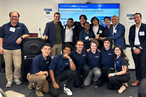 A group of students and mentors pose together indoors in front of a presentation screen displaying “CITRIS Aviation Prize Awards – Atech Award for Most Innovative Design for Air Mobility.” (Photo Credit: Amanda Cairo/Berkeley ITS) 